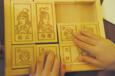 A sliding block puzzle has pictures of a Chinese king, his generals, and the generals of the opposing armies engraved in the wood.  